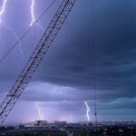 Guindaste atingido por raio em Brasília durante ato político, com tempestade e céu escuro.