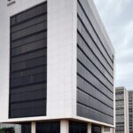 Edifício da Caesb em Brasília sob céu nublado, representando angústia por resultados de concurso.