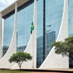 Edifício do Tribunal de Justiça em Brasília com bandeira a meio mastro, simbolizando luto pela morte de desembargador.
