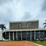 Edifício do Tribunal de Justiça do DF com bandeiras a meio mastro, simbolizando luto pela morte de desembargador.