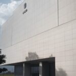 Quadro de avisos com papéis de resultados de concurso em prédio público em Brasília, destacando irregularidades em certame da Caesb.