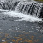 Vista do Reservatório do Descoberto transbordando com chuvas, garantindo água para o DF, em estilo fotojornalístico realista.
