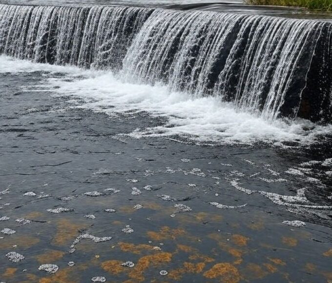 Vista do Reservatório do Descoberto transbordando com chuvas, garantindo água para o DF, em estilo fotojornalístico realista.