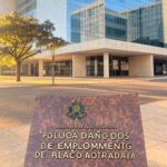 Prédio governamental em Brasília com placa de vagas de emprego para pessoas em situação de rua, representando iniciativa do GDF.