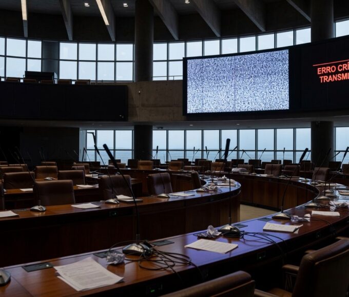 Sala de plenário vazia da CLDF com telas de transmissão ao vivo falhando, destacando ineficiências em sessão ordinária.