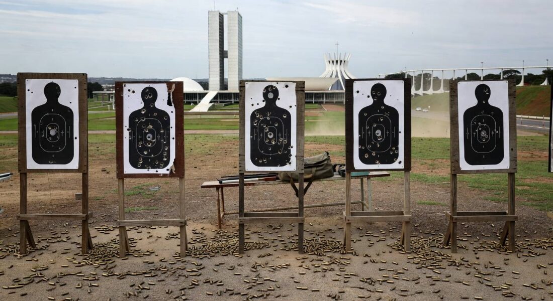 Clube de tiro vazio em Brasília com alvos perfurados e cartuchos no chão, representando temores de proliferação de armas.