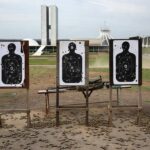 Clube de tiro vazio em Brasília com alvos perfurados e cartuchos no chão, representando temores de proliferação de armas.