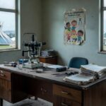 Sala de oftalmologia em Brasília com equipamentos antigos e documentos desorganizados, representando críticas à política de saúde visual infantil da CLDF.