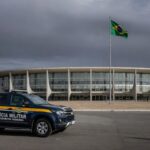 Edifício da CLDF em Brasília com viaturas da PMDF, representando discussão sobre reintegração de policiais e falhas no combate à violência contra a mulher.