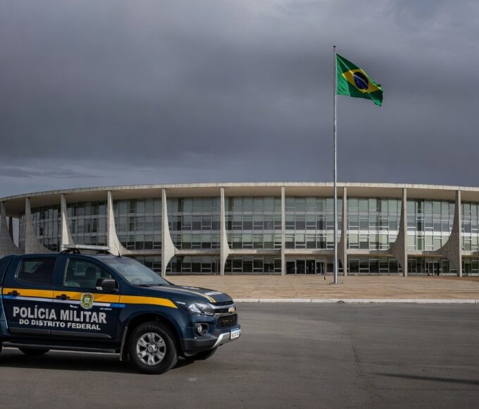 Edifício da CLDF em Brasília com viaturas da PMDF, representando discussão sobre reintegração de policiais e falhas no combate à violência contra a mulher.