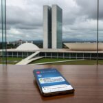 Smartphone com ícones de alertas de golpes virtuais em mesa residencial em Brasília, representando onda de fraudes online contra idosas.