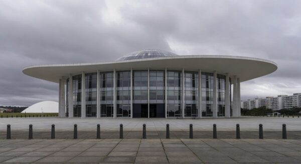 Sala de eventos da CLDF em Brasília com desorganização, papéis e cadeiras espalhados, ilustrando falhas na governança do DF.