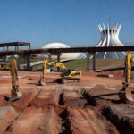 Obras de infraestrutura no DF contra enchentes e trânsito, com máquinas e construções em Brasília.