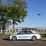 Viatura da PMDF em rua da Asa Norte, Brasília, com drone no céu durante Operação Presença.
