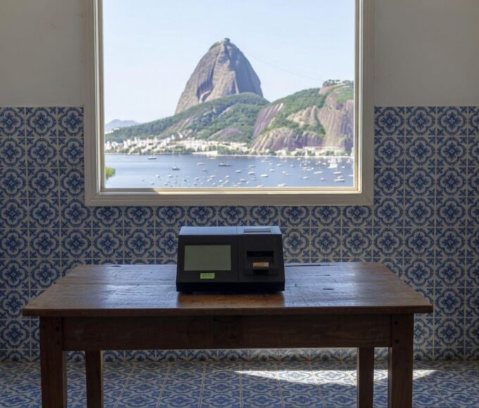 Urna eletrônica em seção eleitoral vazia no Rio de Janeiro, representando eleições diretas para mandato tampão.