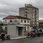Rua em Brasília com motos de motofretistas perto de ponto de apoio, expondo negligência após demora de oito anos.