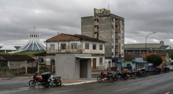 Rua em Brasília com motos de motofretistas perto de ponto de apoio, expondo negligência após demora de oito anos.