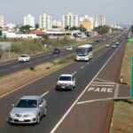 Rodovia BR-070 em Taguatinga e Ceilândia, com tráfego e prédios urbanos, representando estudos para viadutos no DF.
