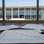 Imagem do Palácio do Buriti em Brasília, com documentos simbolizando decreto de cortes em contratos no DF.