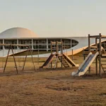 Edifício da Câmara do DF com parque infantil vazio simbolizando negligência em políticas para a primeira infância